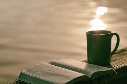 green ceramic mug beside book